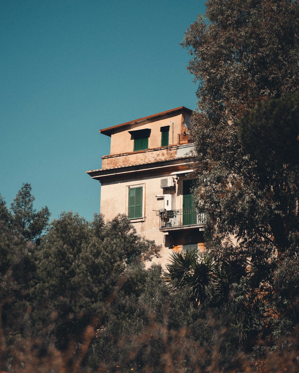 Bâtiment en béton blanc entouré d’arbres verts sous un ciel bleu pendant la journée