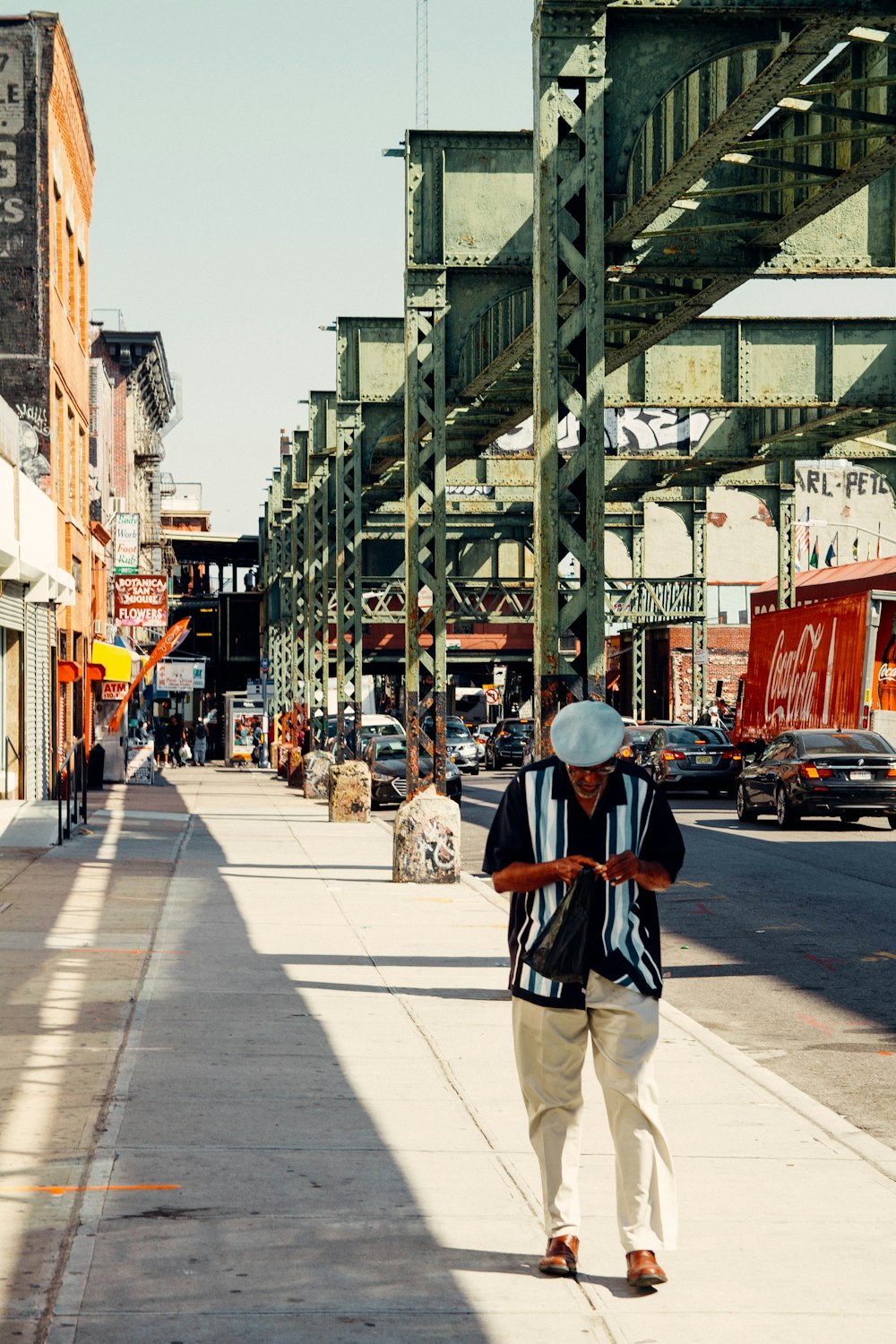 man in black jacket and white pants walking on sidewalk during daytime