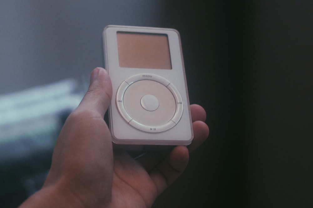 a person holding a small mp3 player in their hand