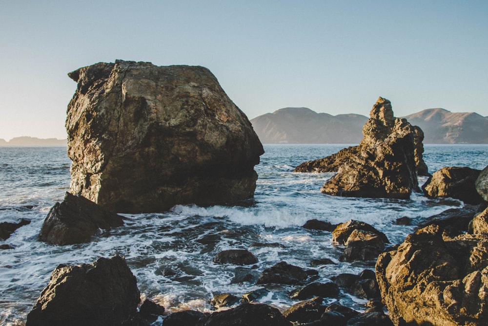 brown rock formation on body of water during daytime