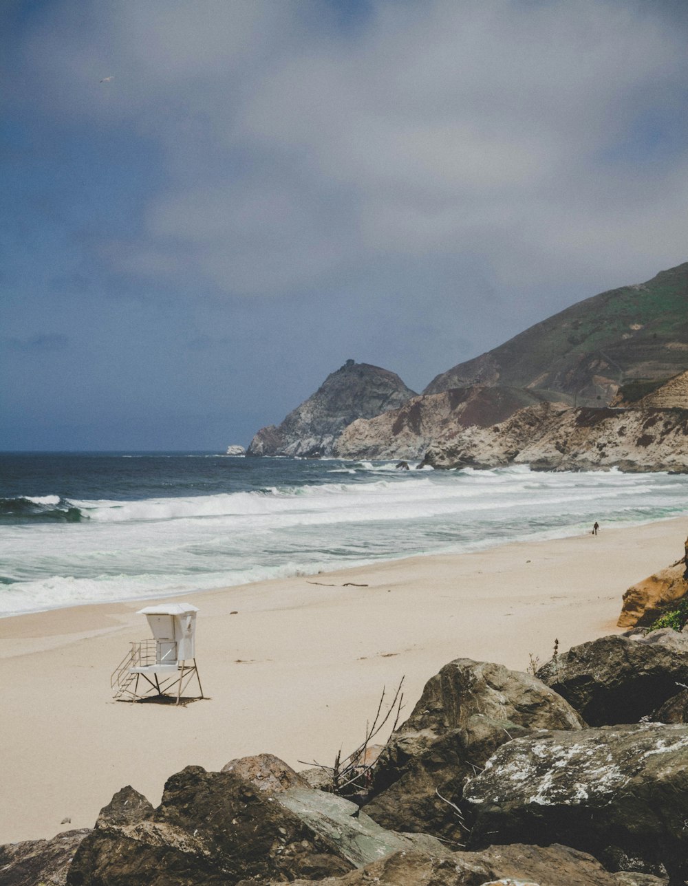 white and brown beach chair on brown sand near body of water during daytime