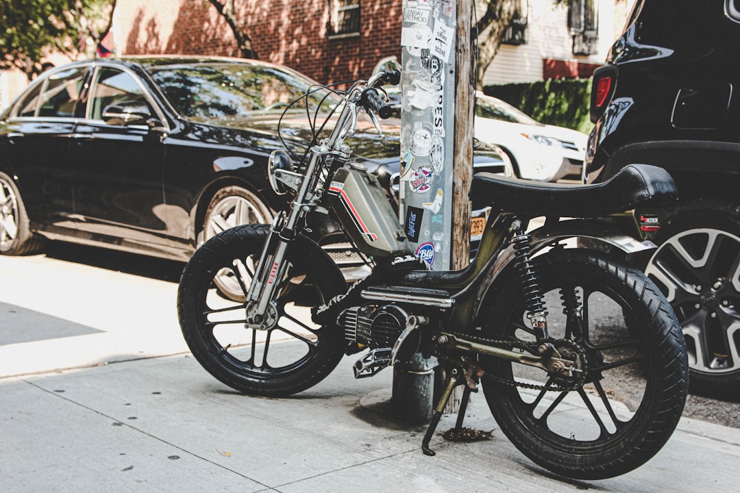 black and gray motorcycle parked beside gray metal post