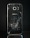 A smartphone with a severely cracked back panel, revealing a spiderweb-like pattern of cracks. The camera and flash are intact, but the damage is extensive.