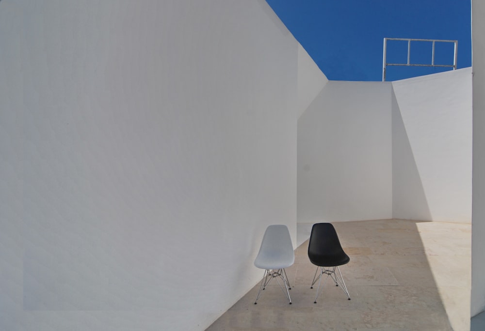 white and black chair beside white wall