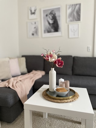 A cozy living room featuring a marble top coffee table, jute braided rug, and canvas landscape prints on the wall.