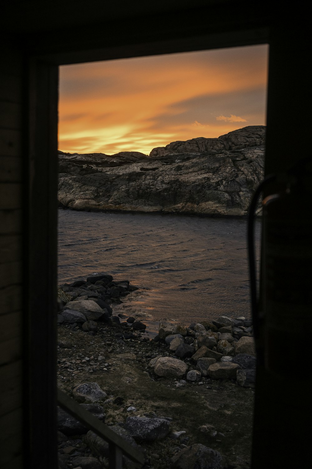 rocky shore near body of water during sunset