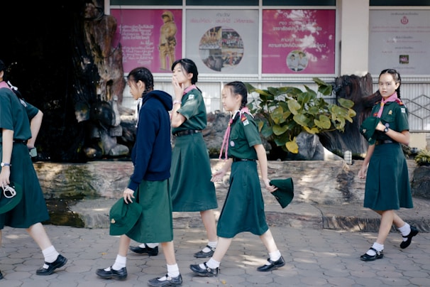 A group of girls in uniform planting trees in the school garden for environmental awareness.