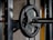 A close-up of the posture brace on a gym bench with weights in the background.
