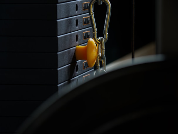 Close-up of a cable machine with weights in a well-lit gym area.