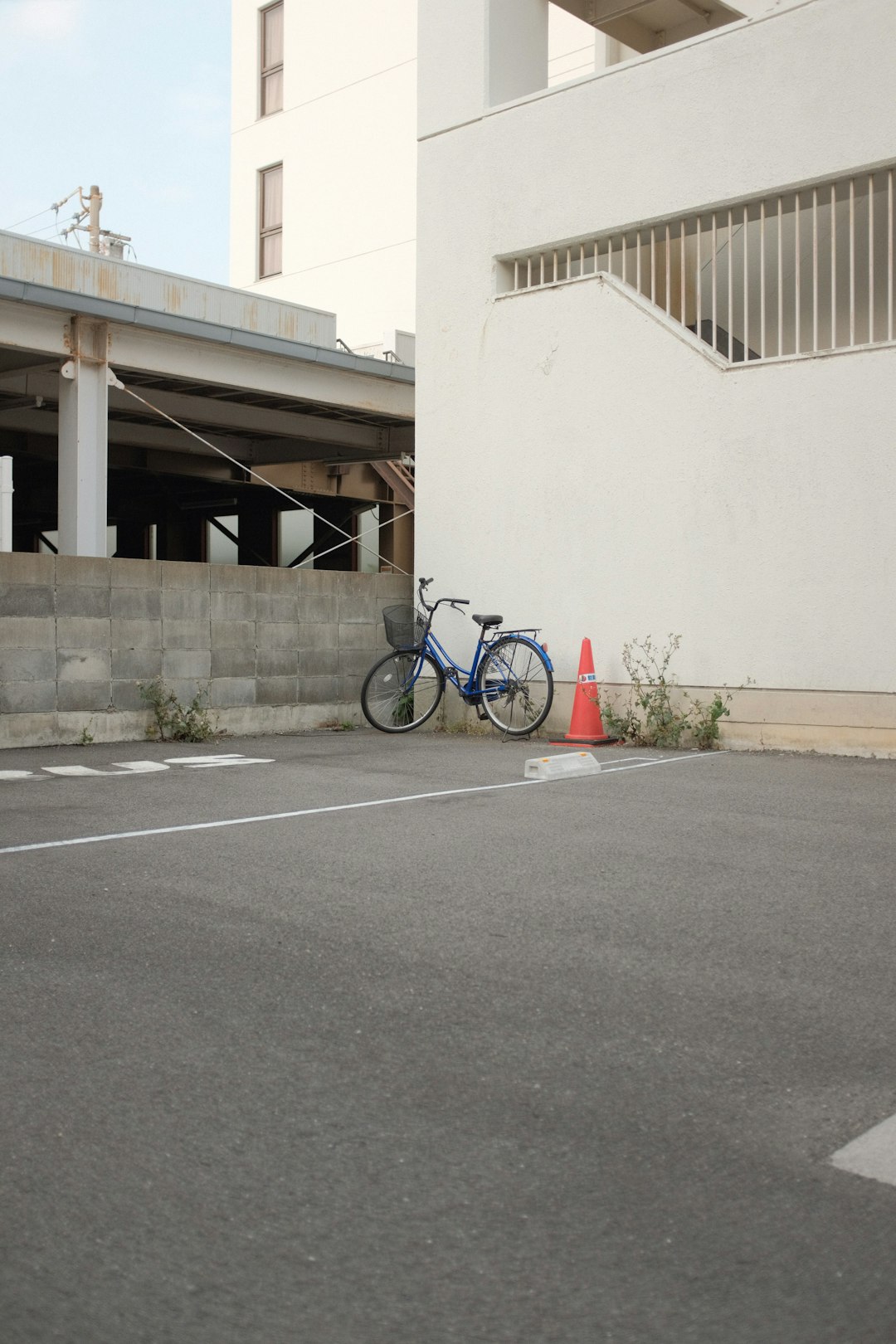 blue bicycle parked beside white concrete building during daytime