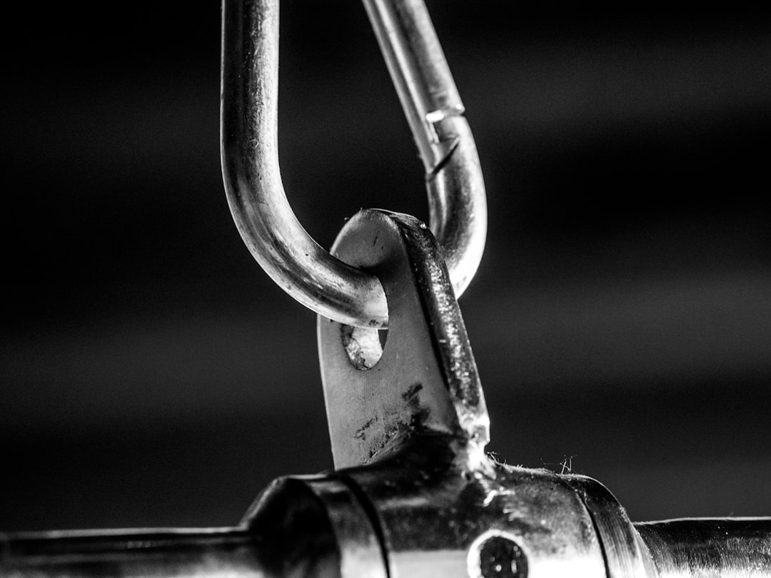 grayscale photo of padlock on metal bar