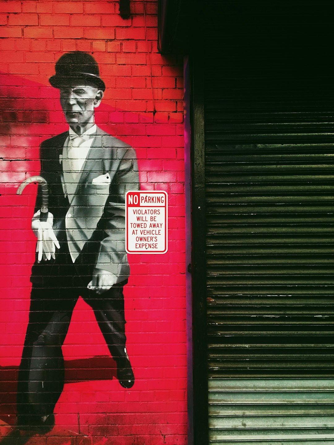 man in black suit standing beside red wall