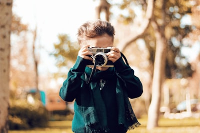 man in blue and black plaid long sleeve shirt holding camera photo teams background