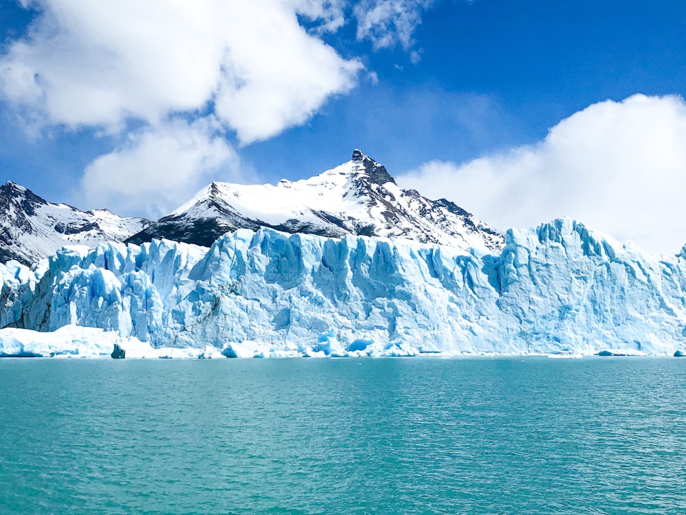 snow covered mountain near body of water during daytime