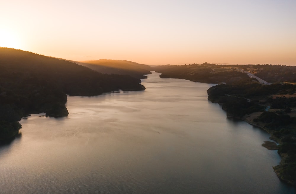 body of water near mountain during sunset