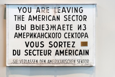 A multilingual sign displaying a warning in four languages: English, Russian, French, and German. It announces the departure from the American sector, indicating historical significance.