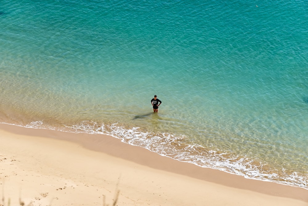 person in black wet suit walking on beach during daytime