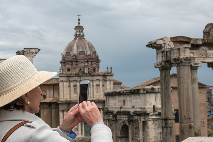 Person capturing ancient architecture with dome and columns on smartphone, symbolizing study abroad 
