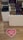 Shelves display a variety of personal care products in bottles and tubes, organized neatly in a store. A visible heart-shaped floor sign with a message encourages social distancing.