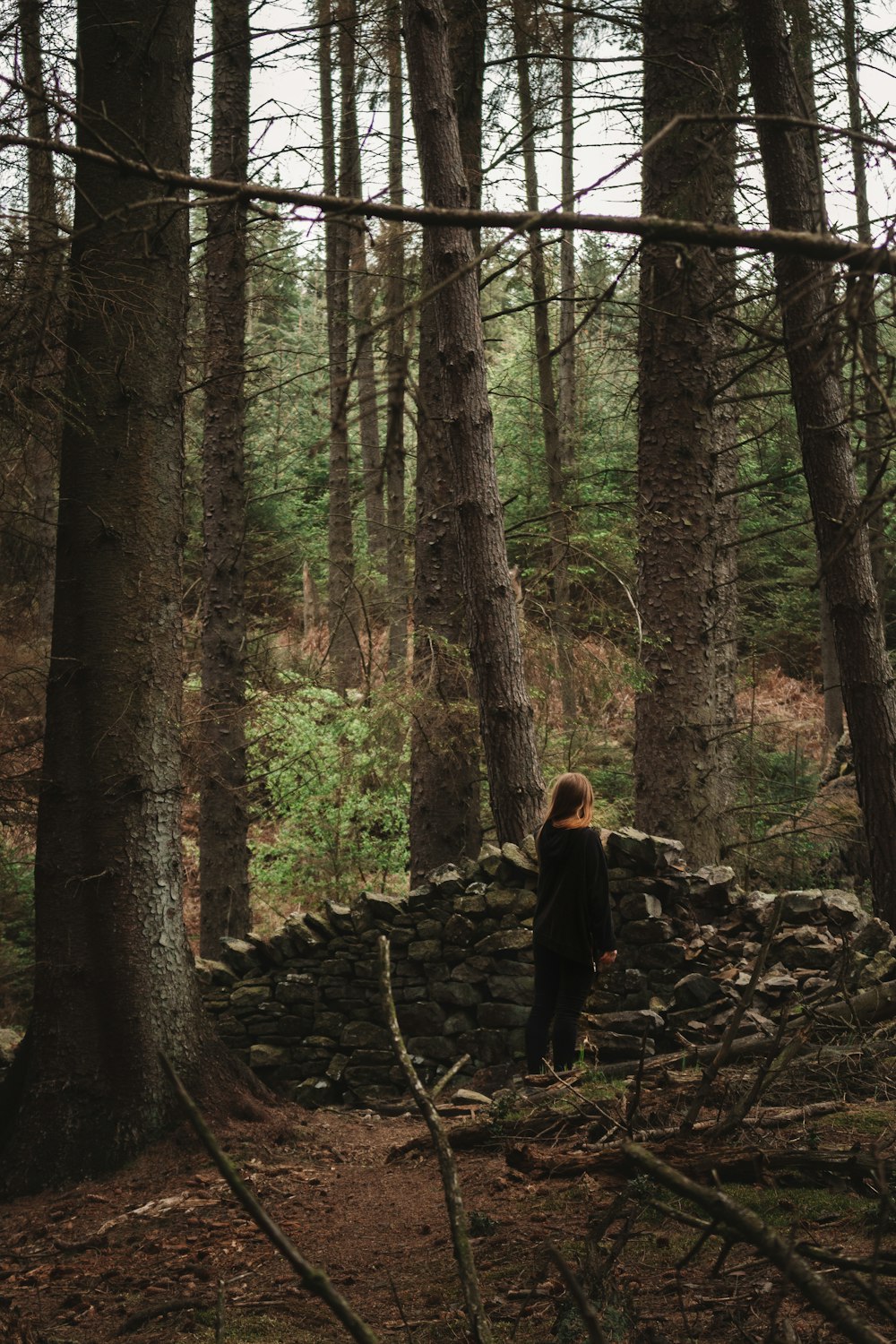donna in giacca nera che cammina sulla foresta durante il giorno