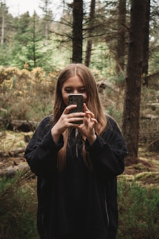 A person taking a photo with a smartphone outdoors in natural light