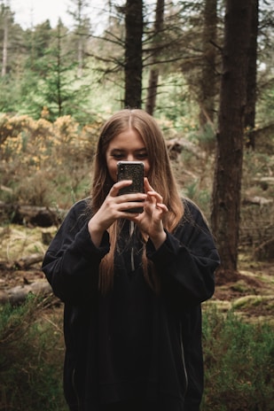 A person taking a photo with a smartphone in natural light.