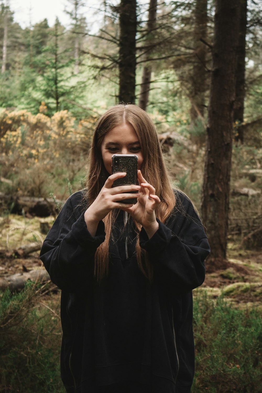 woman in black jacket holding black smartphone