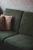 A dark green textured sofa with two striped cushions against a neutral wall