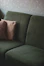A dark green textured sofa with two striped cushions against a neutral wall