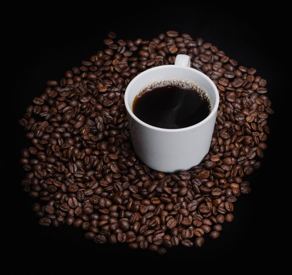 white ceramic mug on coffee beans