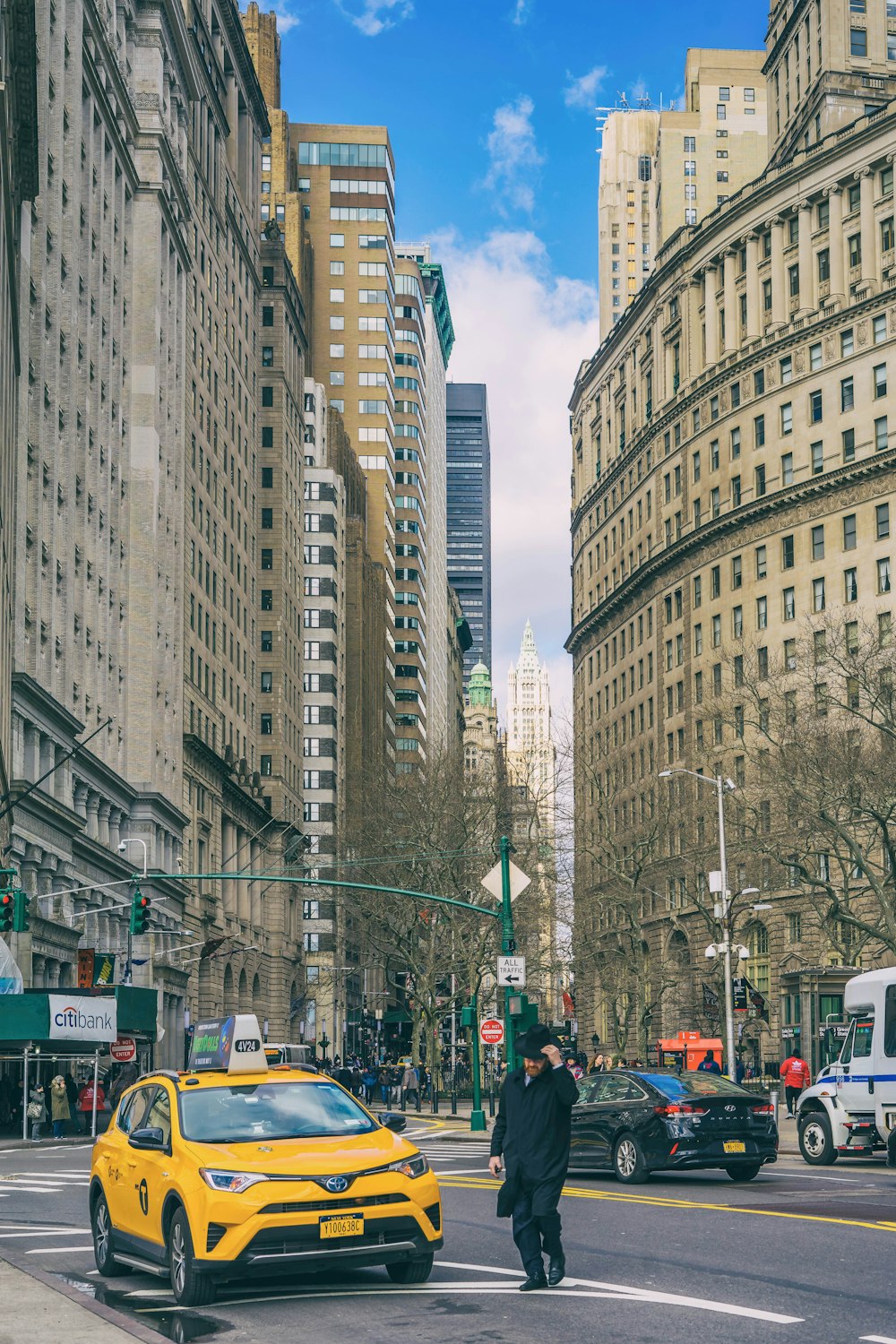 cars on road in between high rise buildings during daytime