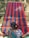 A person is weaving a colorful textile on a traditional loom, with vibrant stripes of red, blue, and green. The textile is stretched across a wooden frame, and the person is wearing a patterned blue garment.