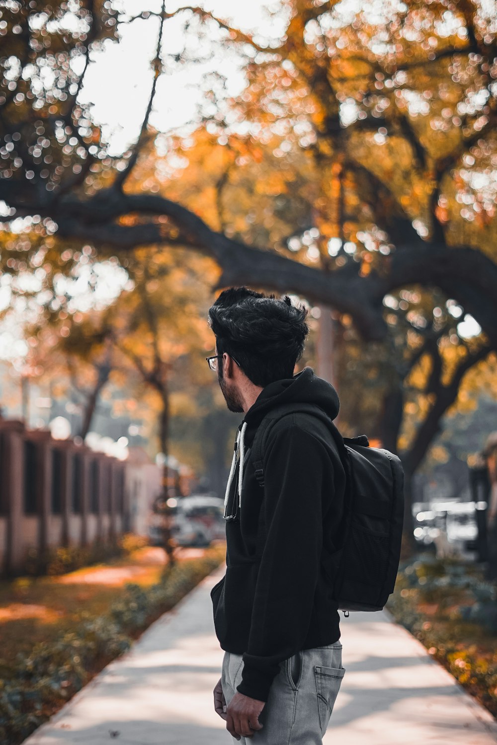 man in black jacket standing near brown trees during daytime