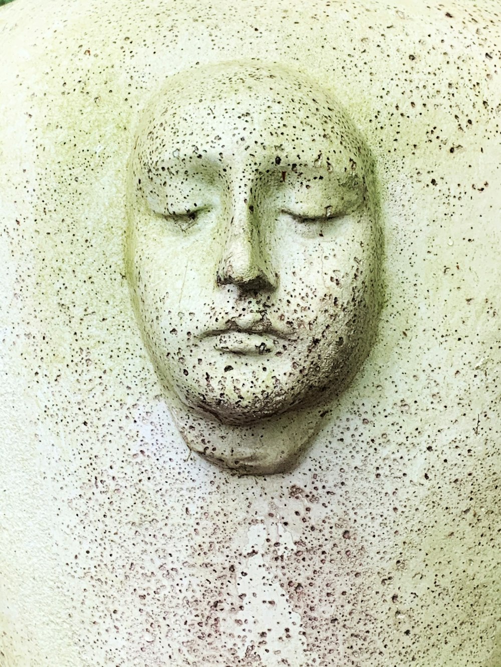 visage humain blanc sculpté sur un mur blanc