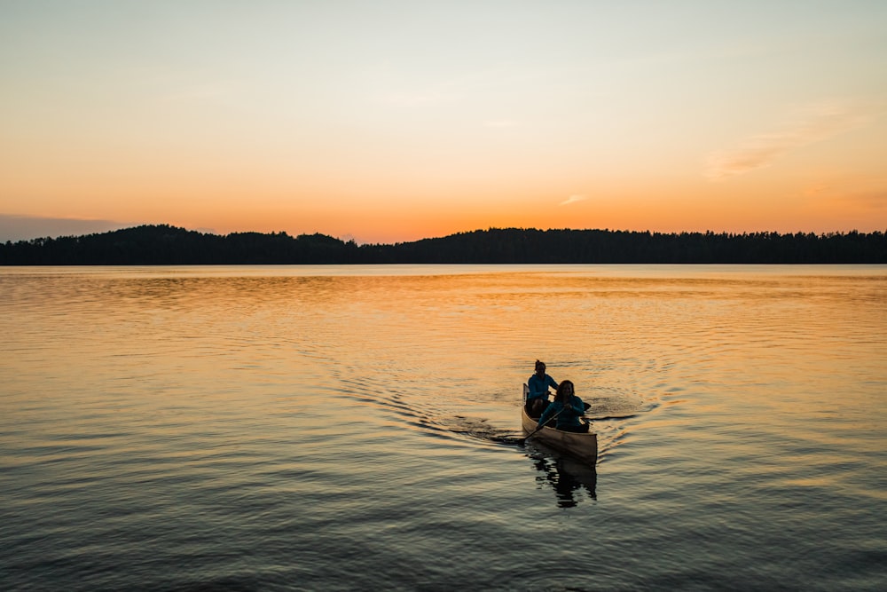 silhouette of 2 people riding on boat during sunset