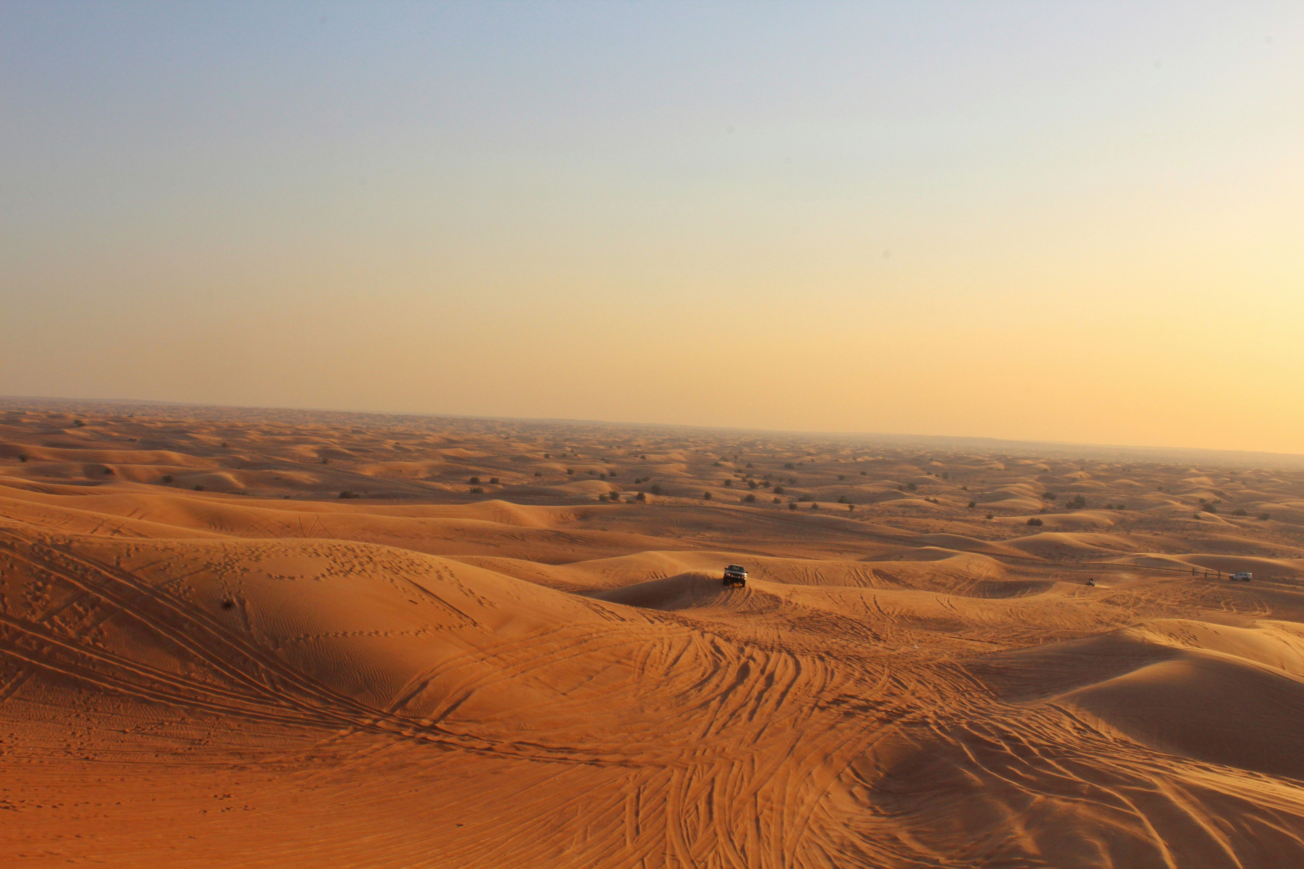 4x4 vehicle driving over golden sand dunes during Dubai desert safari at sunset