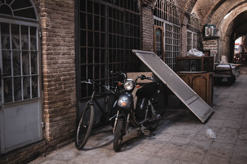 black motorcycle parked beside brown brick wall