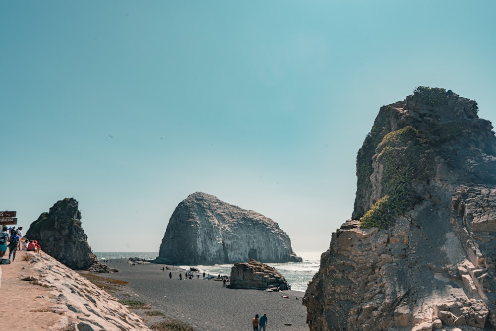 people walking on beach near rocky mountain during daytime