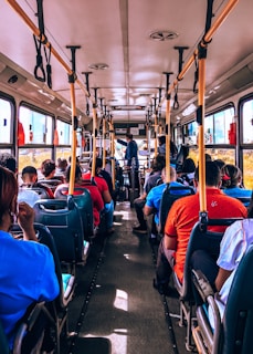Children happily seated inside the bus, looking out the window on a bright day.