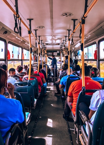 Children happily seated inside the bus, looking out the window on a bright day.