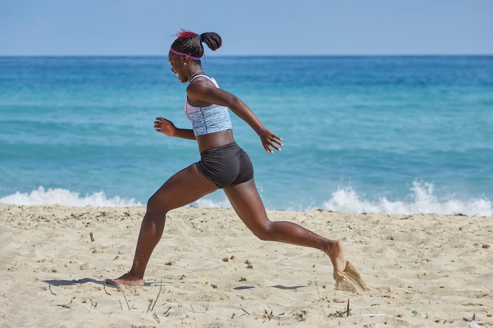 woman in white sports bra and blue denim shorts running on beach during daytime