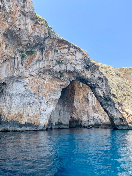 brown and gray rock formation beside blue sea under blue sky during daytime in Blue Grotto Malta