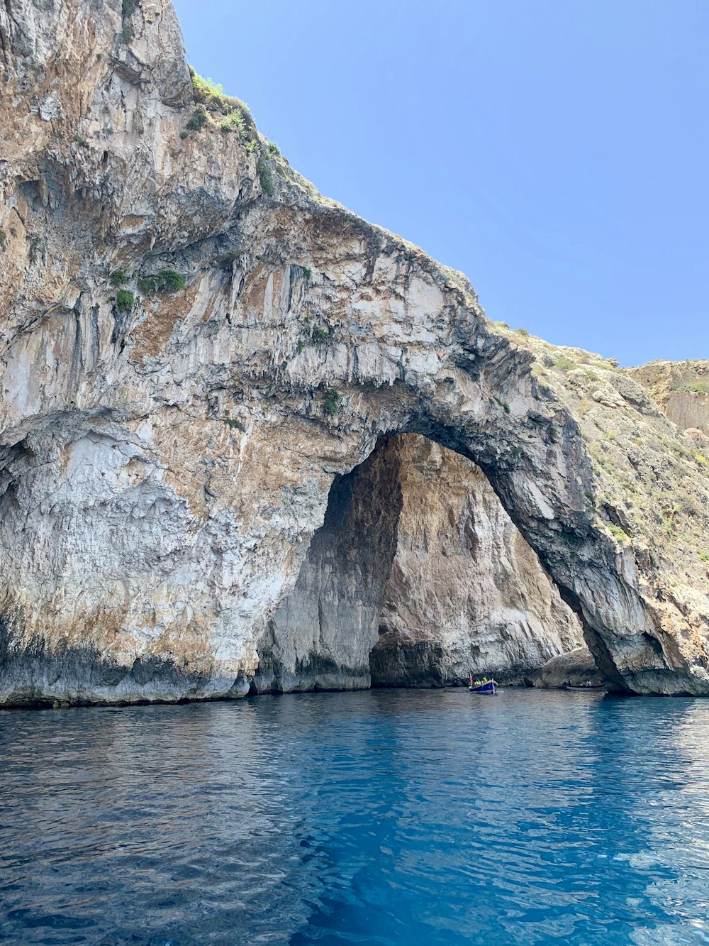 brown and gray rock formation beside blue sea under blue sky during daytime