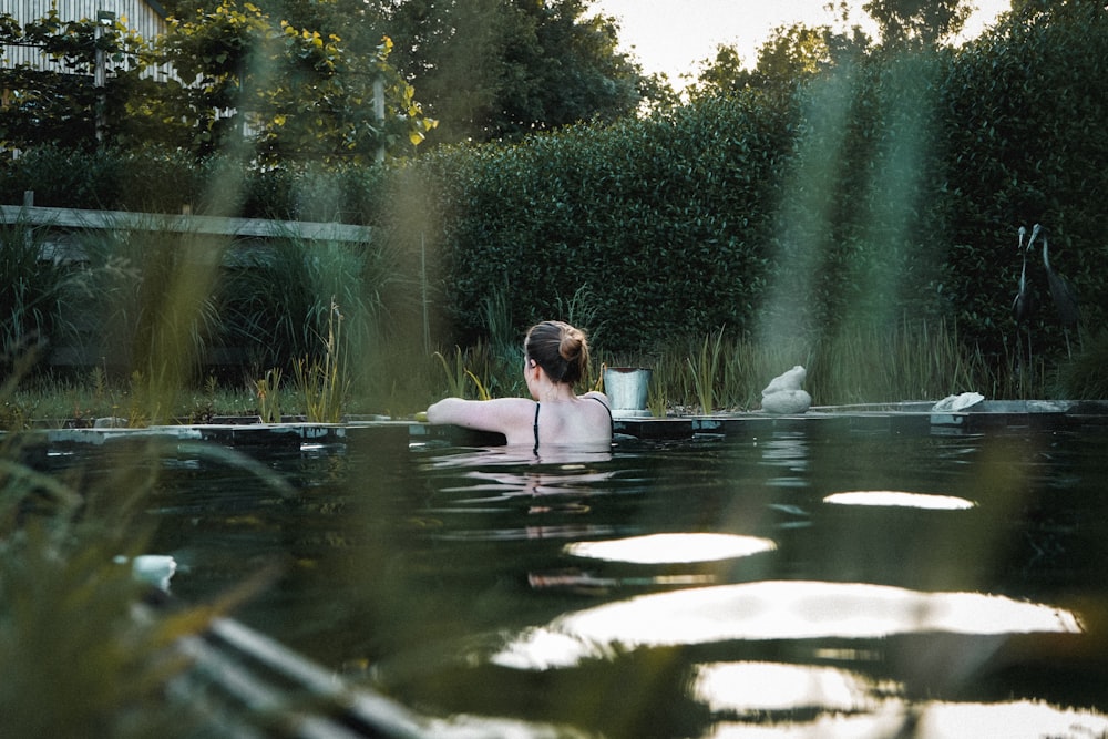 woman in water in the middle of green trees during daytime