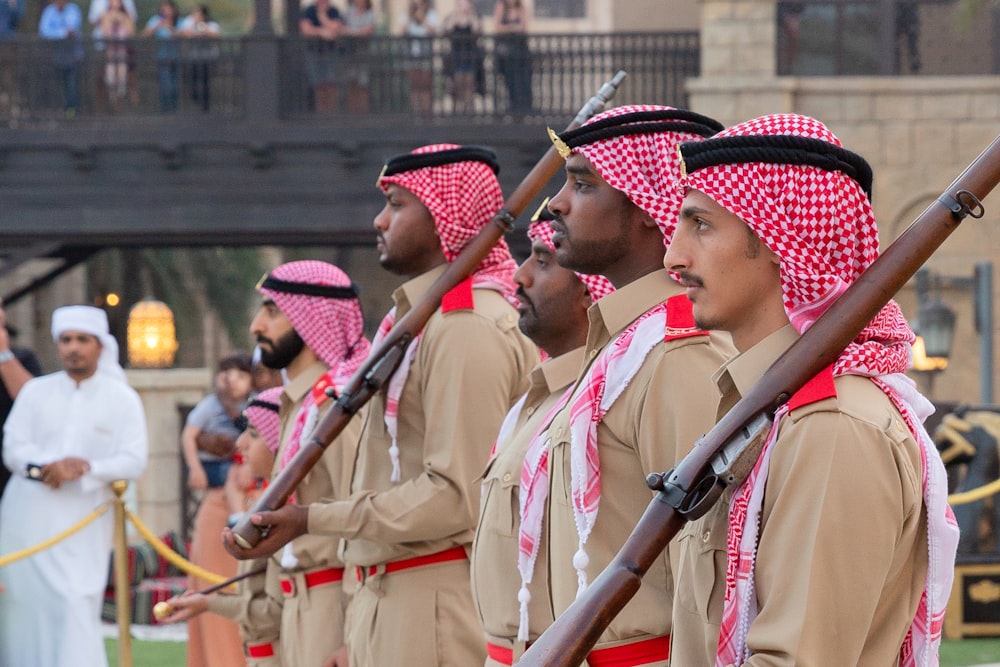 men in brown uniform holding rifle during daytime