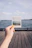 Close-up of a hand holding a vibrant yellow zinc stick with ocean waves in the background.
