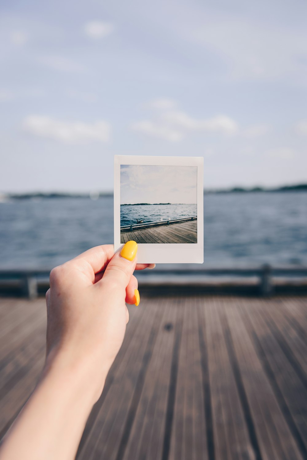 person holding white picture of body of water during daytime