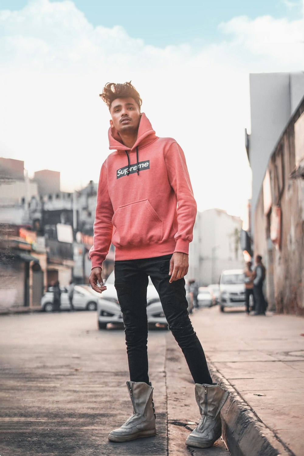 woman in pink pullover hoodie standing on sidewalk during daytime