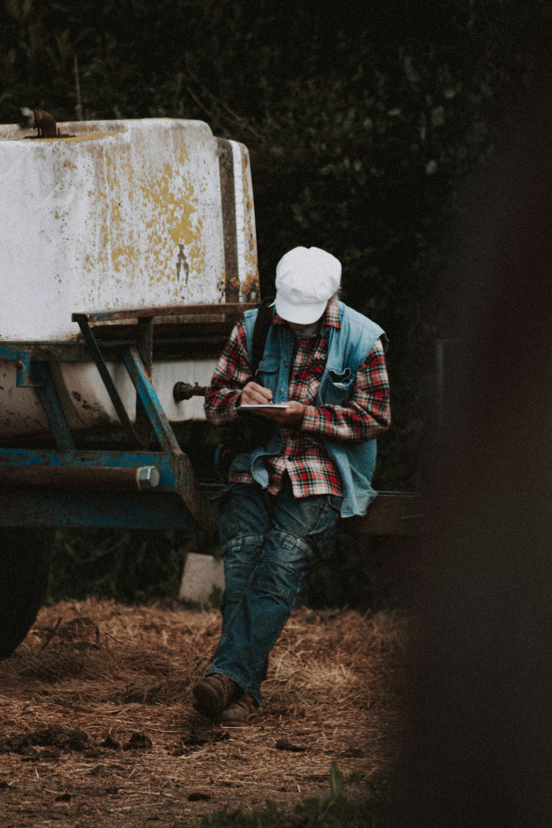 man in blue denim jacket and blue denim jeans sitting on brown wooden trailer during daytime