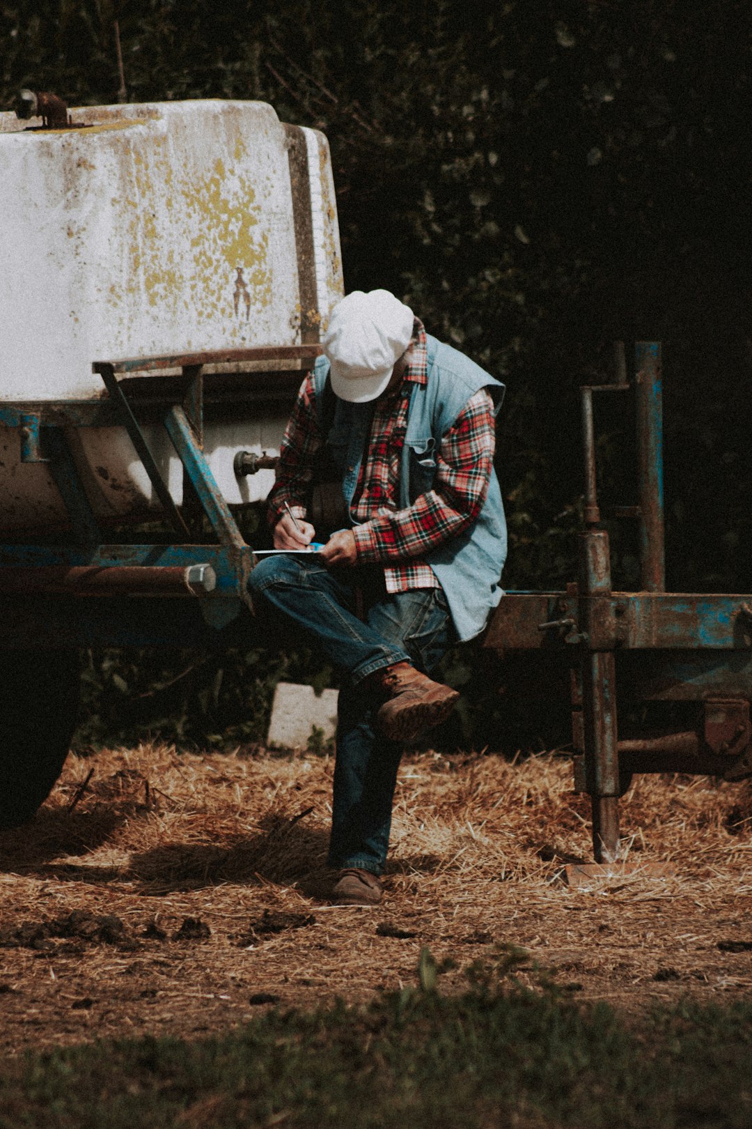 man in red white and blue plaid dress shirt and blue denim jeans sitting on brown